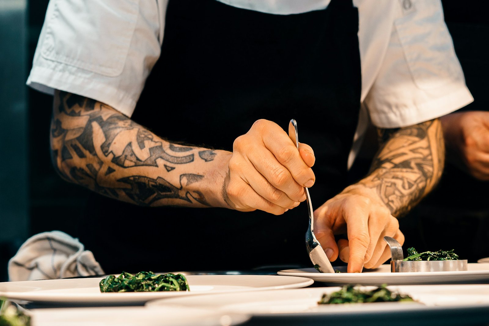 Chef plating a dish at the pass in a restaurant kitchen
