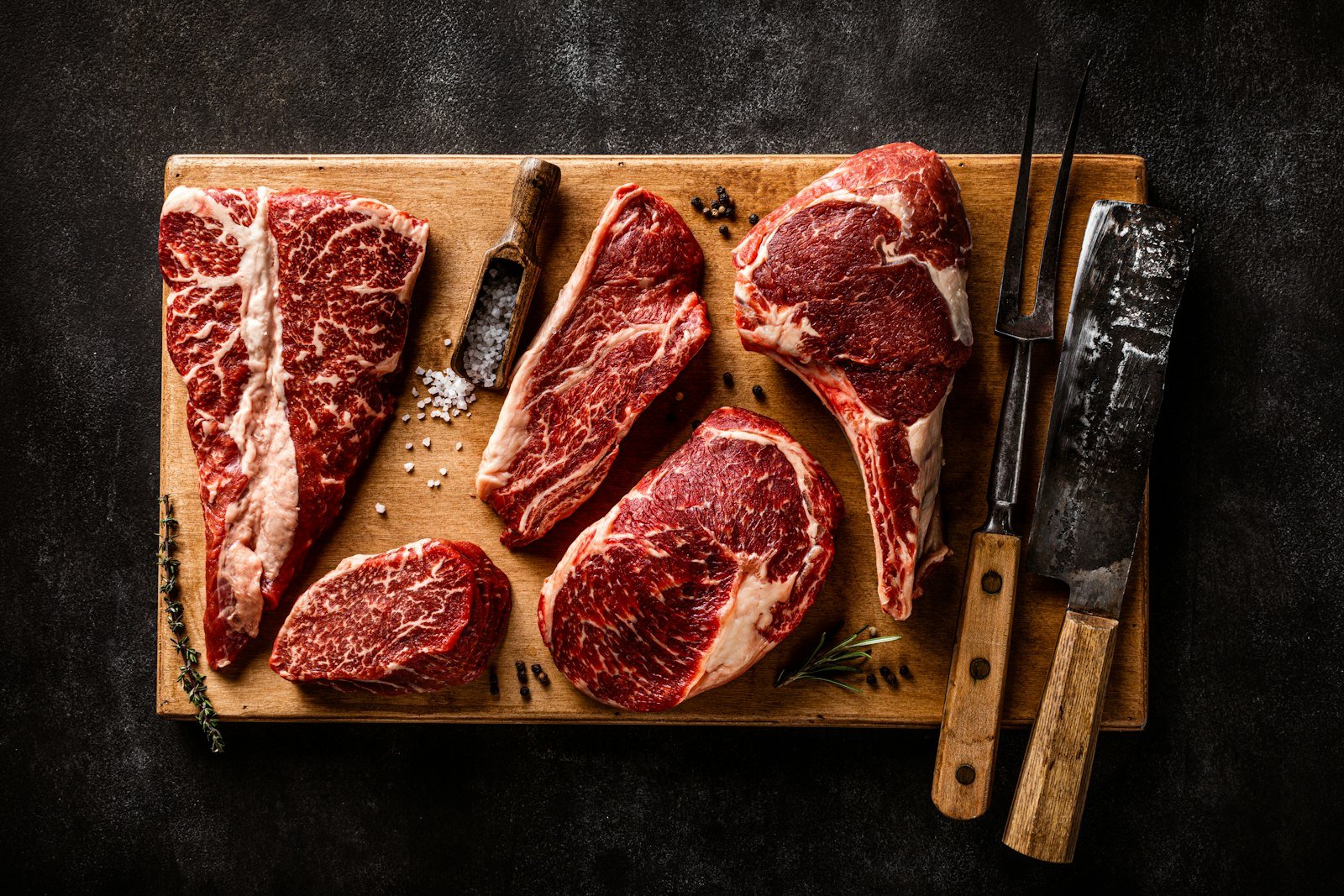Steaks and a knife on a wooden cutting board