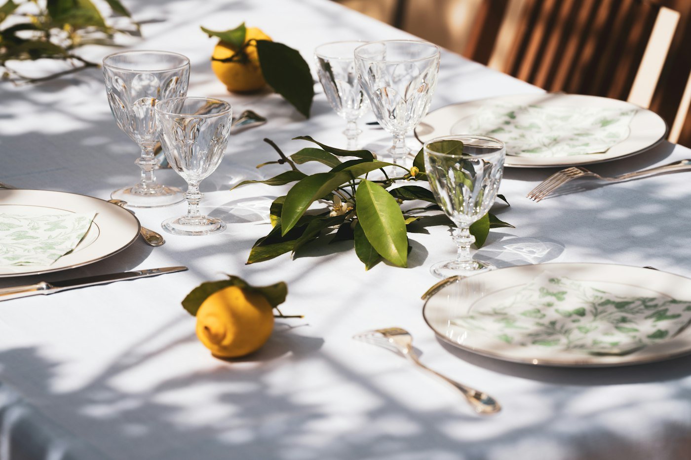 Table set with white plates, crystal glasses and fresh greenery