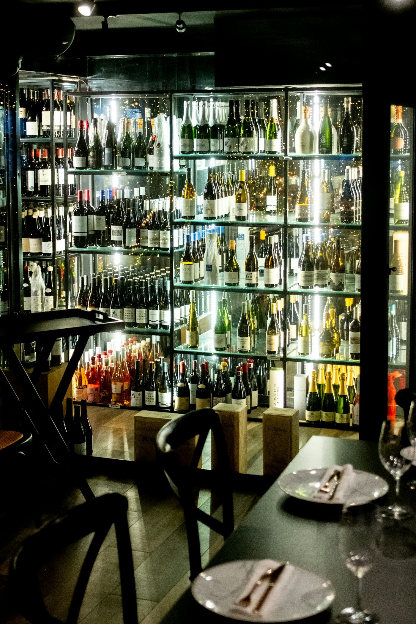 Wall of wine bottles displayed in a dimly lit wine bar